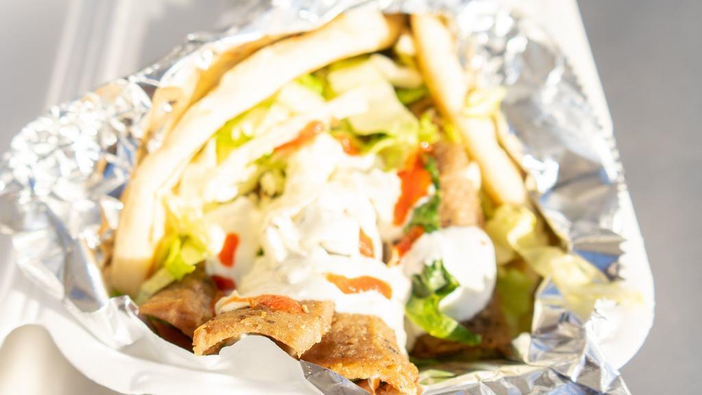 Lamb Gyro · Lamb cooked with a vertical broiler the authentic way, served on Pita with lettuce, cucumbers, tomatoes, onions, pepperoncinis topped off with homemade tzitiki sauce, white sauce and hot sauce.