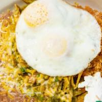 Chilaquiles Con Huevos · Pieces of fried tortilla simmered in red sauce. Topped with onions, cilantro & sour cream.