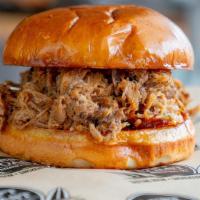 Smoked Pulled Pork Which · Smoked pulled pork with BBQ sauce, and pickles on a brioche bun