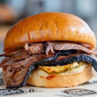 Smoked Brisket Which · Smoked Brisket with BBQ sauce and pickles on a brioche bun