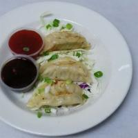 Seared Pot Stickers · Steamed and pan seared chicken dumplings, topped with green onion and served over Asian slaw...