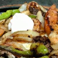 Surf And Turf Fajitas · Steak grilled with shrimp, onion, tomato, bell pepper, and melted cheese topped with a dollo...