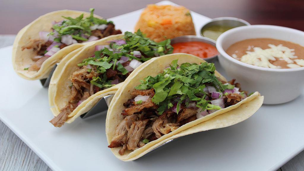 Tacos Carnitas · Three corn tortillas filled with savory fried pork, onions, and cilantro. Served with rice and beans.