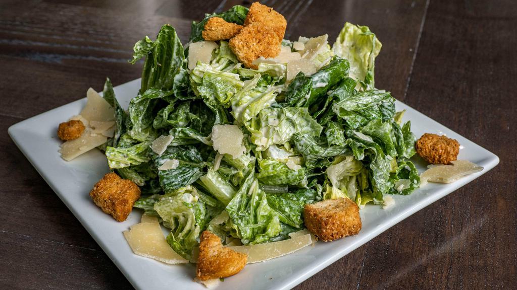 Caesar Salad · Crisp romaine lettuce tossed in our housemade Caesar dressing, then topped with shaved Parmesan cheese and seasoned croutons. Add chicken for additional charge.