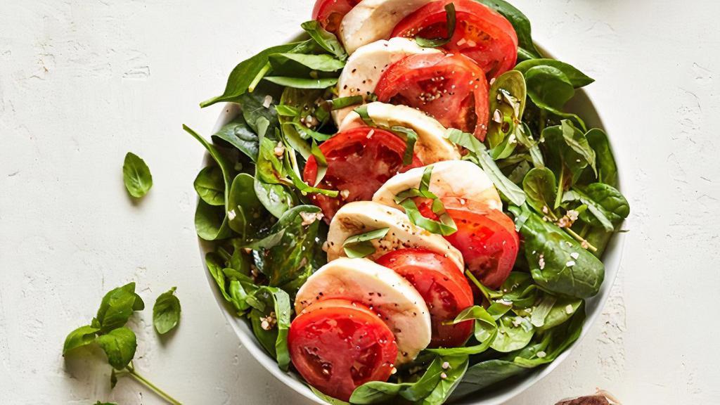 Caprese · The Caprese Salad: Fresh spinach served with fresh mozzarella, roma tomatoes, basil and garlic, topped with cracked black pepper, and olive oil. Served with house-made balsamic vinaigrette tossed in or available on the side..