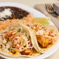 Fish Tacos · Two soft tacos with crispy fish on corn tortillas, topped with cabbage, white cream sauce, a...