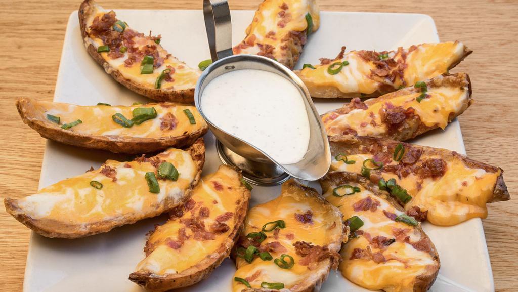 Potato Skins · Crispy potato skins topped with melted Monterey Jack and Cheddar cheeses, bacon bits, and scallions.