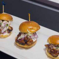 Pulled Pork Sliders · Three pulled pork sliders covered in BBQ sauce and coleslaw.