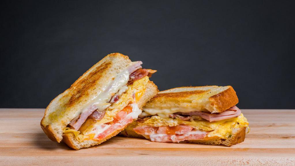 Breakfast Club Melt · Thick grilled sourdough bread with scrambled eggs, ham, bacon, american and swiss cheese, tomato and mayonnaise.