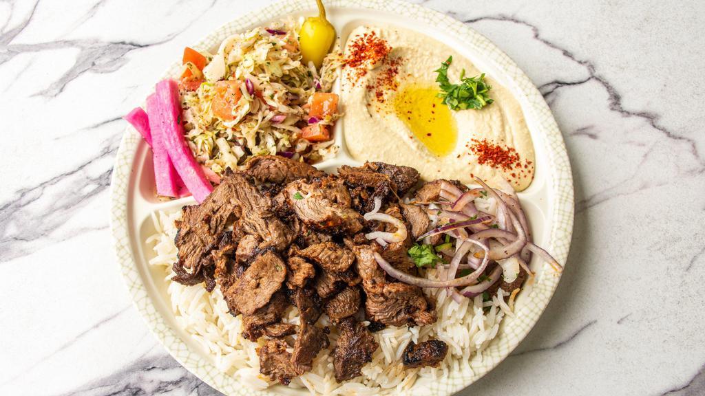 Beef Shawarma Plate · Marinated beef shawarma strips served with hummus, tahini sauce, tomato, lettuce red onions, pickles, and pita bread.