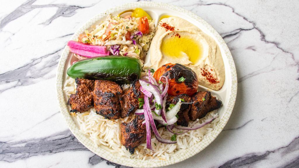 Beef Shish Kabab Plate · Marinated beef tender served with rice, red onions, roasted tomato, pepper, pickles, hummus, lettuce salad, and pita bread.