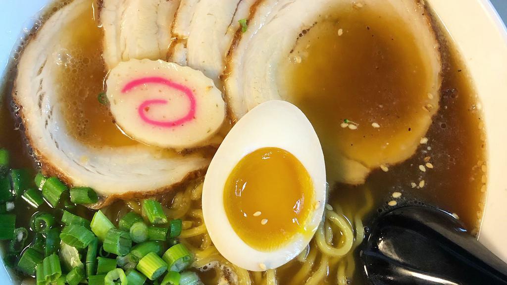 Shoyu Ramen · Soy Sauce base pork broth, ramen noodles, with slices of Chashu, green onion, soft boiled egg, fish cake, and sesame seeds.