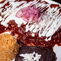Enchiladas Dona Paula · Two fried corn tortilla covered with Mom’s Chile Ancho Mole Sauce, folded in half and filled...