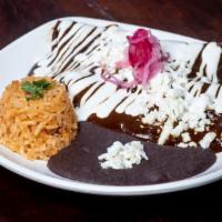 Enchiladas Poblanas · Two fried corn tortillas covered with multi chile pod, sweet and spicy mole poblano sauce, f...