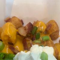 Loaded Tots · Crispy tater tots topped with nacho cheese, bacon,  onions and sour cream.