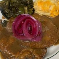 Smothered Pork Chop · Two fried pork chops smothered in roux brown gravy and pickled onions with your choice of tw...