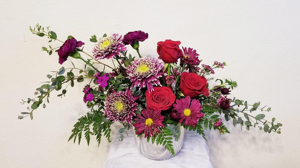 Fuchsia Passion · Enjoy this gorgeous arrangement filled with dark red Roses, Fuchsia Carnation, Daisy, Chrysanthemum and accented with assorted greens. This arrangement is amazing complement to any desk, dinner table, or to send 