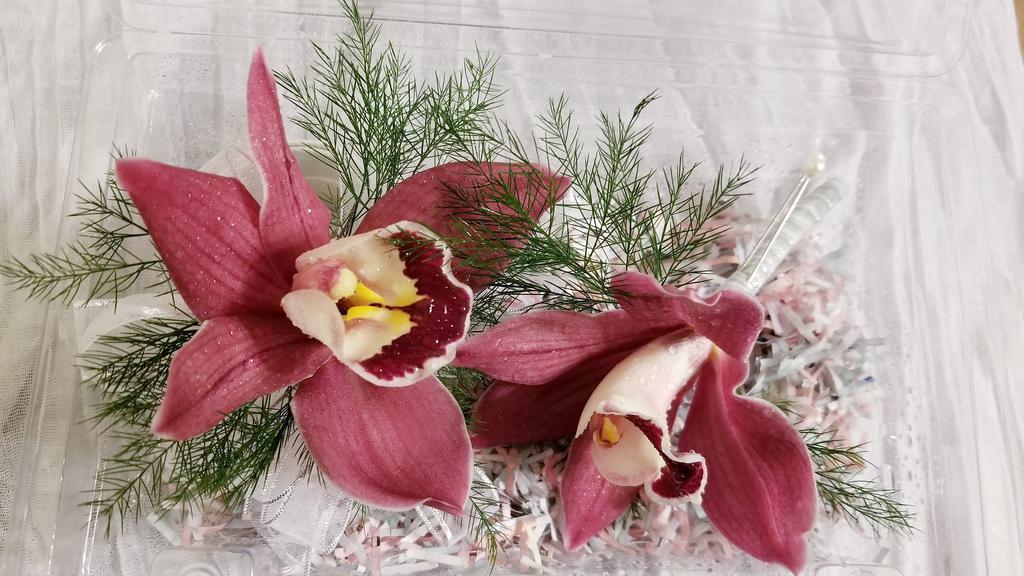 Burgundy Cymbidium Orchid Wrist Corsage And Boutonniere  · Set of wrist corsage and boutonniere design using cymbidium orchids, greenery and white/silver ribbon. 

NOTE:  All selections shown are representative of the arrangements that we can prepare for you, however due to flower availability and seasonal variations we may not be able to fill your order exactly as illustrated. Your order will be filled to the specified amount with products of an equal or greater value.  As Flower are sensitive items, the size, shade, bloom, and color might difference from the image shown.