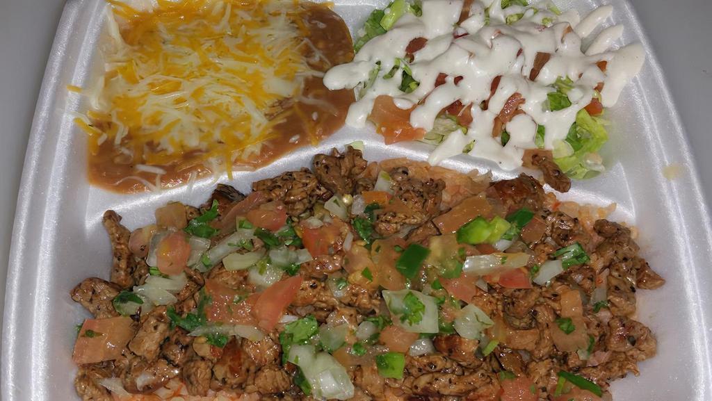 Spanish Rice Asada Plate · Spanish rice covered in marinated steak meat and spicy Pico de Gallo, refried beans with cheese, and a salad.