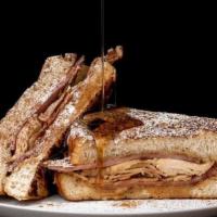 Monte Cristo Sandwich · House baked sourdough French toast stuffed with ham, turkey and swiss cheese.  Served with h...