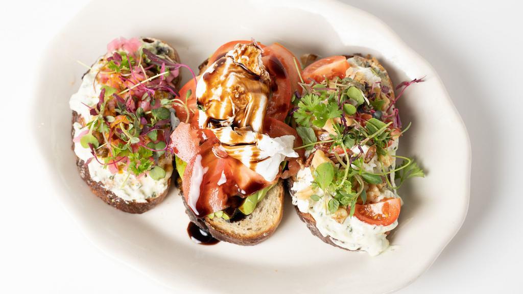 Avocado Toast Flight · Combination of three avocados toast made on our housemade multi-grain bread :
1st : Goast cheese, walnut, tomatoes and honey toast.
2nd : Fried egg, tomato, balsamic reduction toast. 3rd : Curry, capers and pickles red onions toast