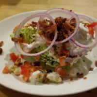 Wedge Salad (Gf) · quarter iceberg lettuce with blue cheese crumbles, chopped bacon, red onion, tomato, and blu...
