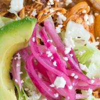 Tinga Tostada · Thin layer of refried beans, shredded spicy chipotle chicken topped with lettuce, sour cream...
