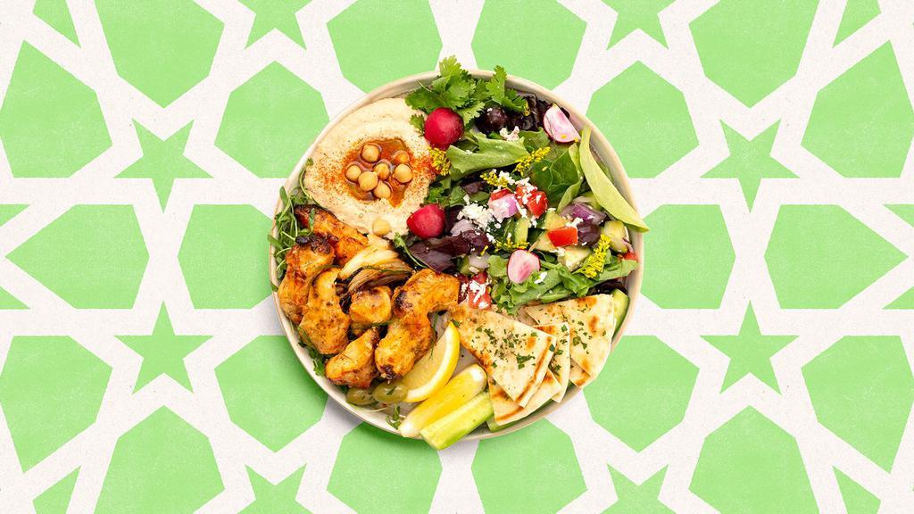 Chicken Kabob Hummus Plate · Chicken kabob with hummus, salad, and pita bread.