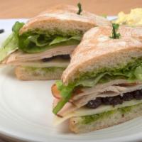 Turkey Cranberry · Sliced turkey breast, dried cranberries, provolone cheese, lettuce, and pesto sauce on a rus...