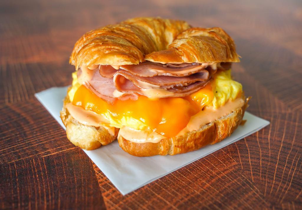Croissant, Ham, Egg, & Cheddar Sandwich · 2 scrambled eggs, melted Cheddar cheese, sliced ham, and Sriracha aioli on a warm croissant.