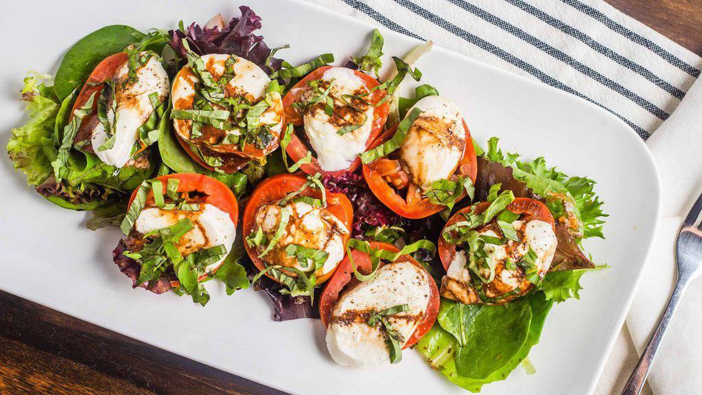 Mozzarella Caprese · Fresh buffalo mozzarella and sliced Roma tomatoes garnished with basil, mixed greens and our balsamic reduction.