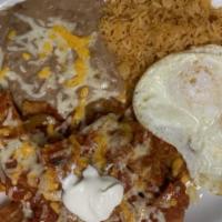 Chilaquiles Con Huevos · Two eggs and chilaquiles topped with sour cream.