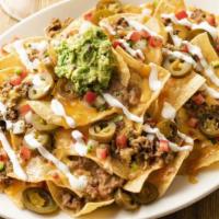 Stacked Nachos · Chips piled high with seasoned ground beef, refried beans and queso. Topped with lime crema,...