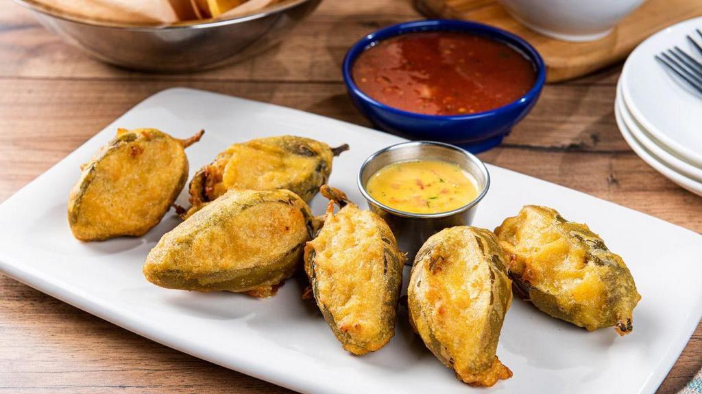 Firecracker Stuffed Jalapeños · Handmade, tempura-fried jalapeños filled with mixed cheese and chicken. Served with our signature queso.