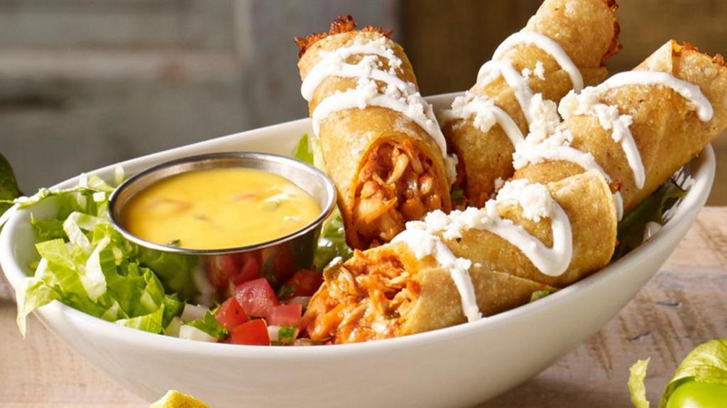 Chicken Flautas · Two hand-rolled yellow corn tortillas filled with chicken tinga and fried golden. Topped with a lime crema drizzle and queso fresco. Served with a side of pico de gallo and queso for dipping.