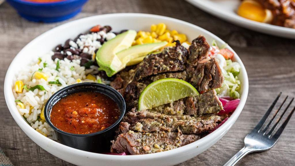 Grilled Steak Border Bowl · Grilled steak brushed with lime-cilantro chimichurri, cilantro lime rice, black beans, pickled red onions, toasted corn, queso fresco, shredded lettuce, pico de gallo, lime crema and sliced avocado.