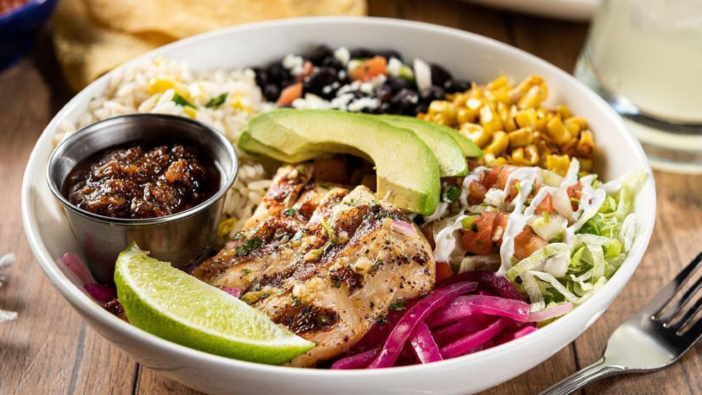 Grilled Chicken Border Bowl · Grilled chicken brushed with lime-cilantro chimichurri, cilantro lime rice, black beans, pickled red onions, toasted corn, queso fresco, shredded lettuce, pico de gallo, lime crema and sliced avocado.