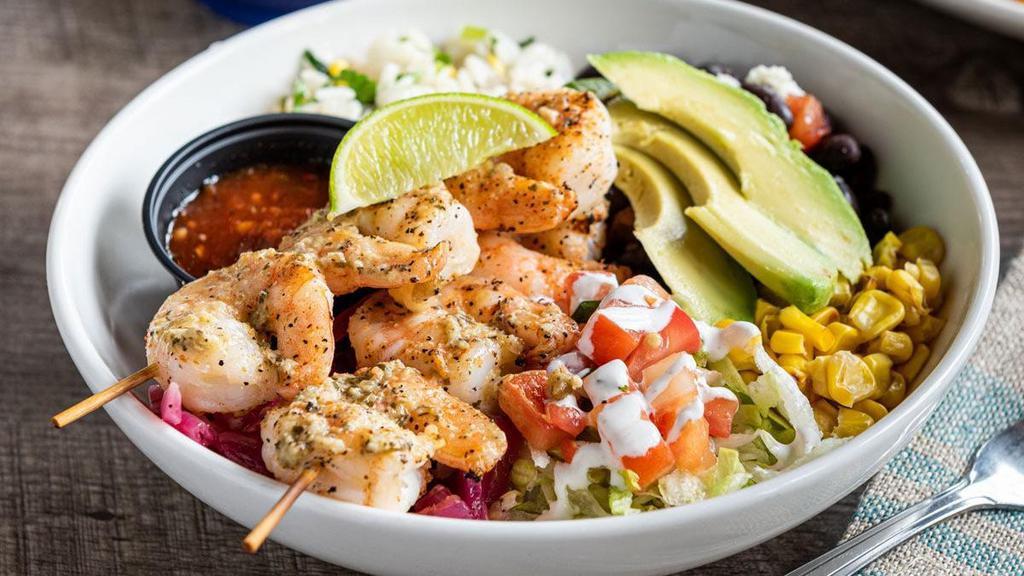 Grilled Shrimp Border Bowl · Grilled shrimp brushed with lime-cilantro chimichurri, cilantro lime rice, black beans, pickled red onions, toasted corn, queso fresco, shredded lettuce, pico de gallo, lime crema and sliced avocado.