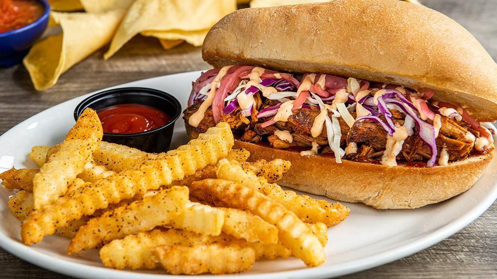 Braised Carnitas Torta · Braised carnitas with creamy red chile sauce and honey-chipotle sauce, topped with shredded cabbage, pickled red onions in a toasted bolillo roll.