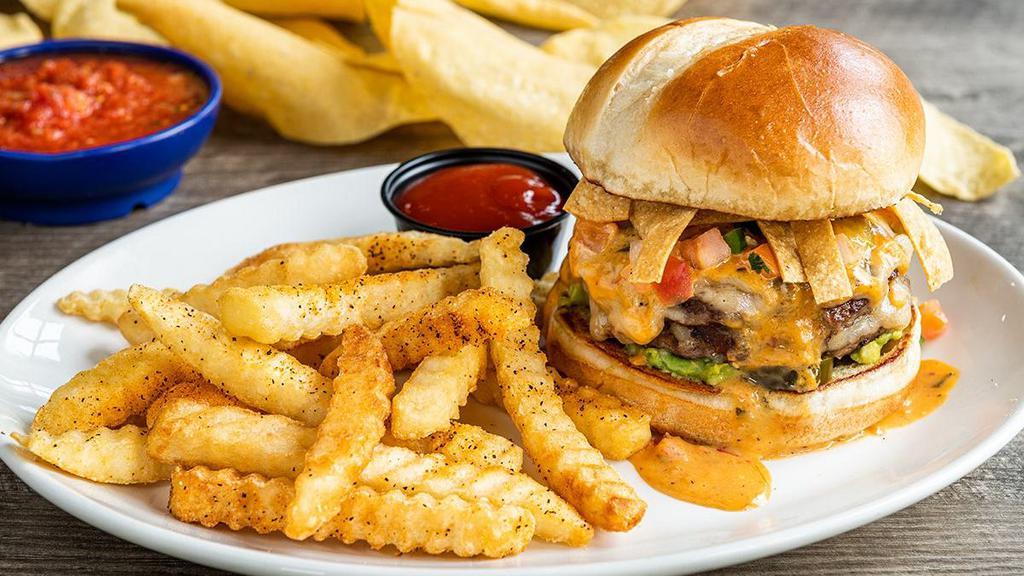 Loaded Queso Burger · Our Tex-Mex burger loaded with fresh guacamole, pico de gallo, tortilla strips pickled jalapeños, Mexican white cheese and covered in smoky queso.