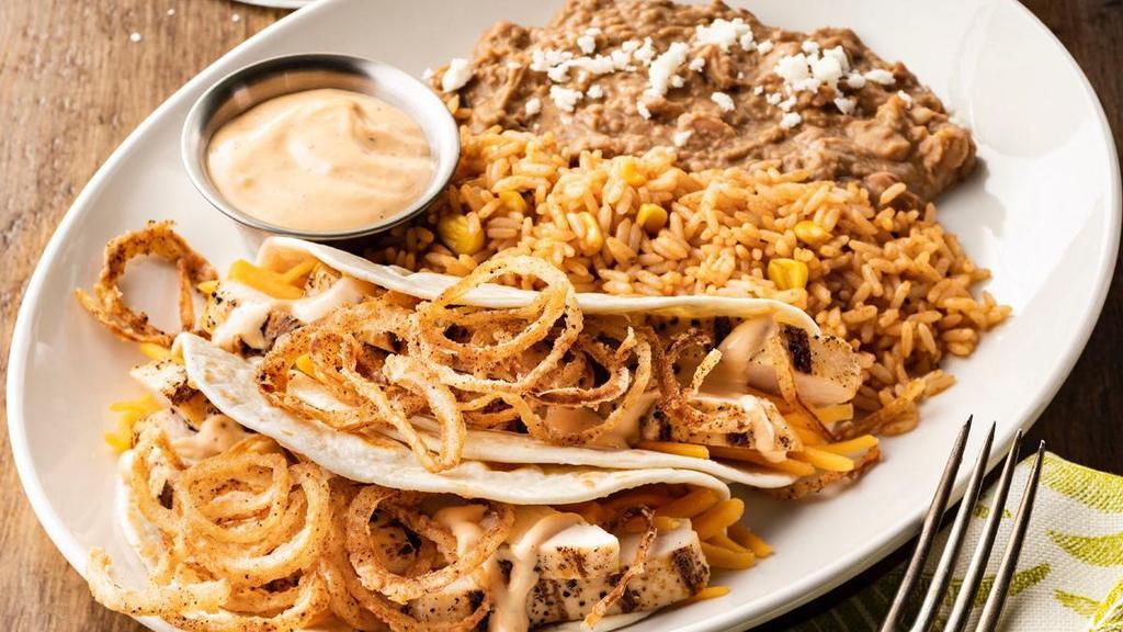 Southwest Chicken Tacos · Mesquite-grilled chicken, cheddar cheese, creamy red chile sauce and fried onion strings in hand-pressed flour tortillas. Served with Mexican rice and choice of beans.