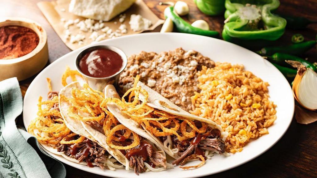 Brisket Tacos · Shredded beef brisket, Jack cheese, fried onion strings and jalapeño-BBQ sauce in hand-pressed flour tortillas. Served with Mexican rice and choice of beans.