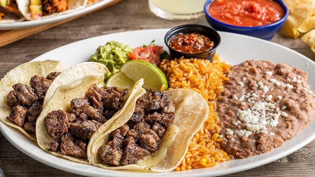 Tacos Al Carbon · Fajita chicken or steak and Jack cheese in white corn tortillas. Served with pico de gallo, fresh guacamole and roasted red chile tomatillo salsa. Served with Mexican rice and choice of beans.