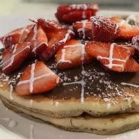 Strawberry Nutella Pancakes · Three fluffy pancakes with Nutella chocolate on each layer garnished with fresh strawberries.