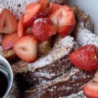 Challah French Toast · Topped with powered sugar and fresh strawberries, served with a side of turkey bacon.