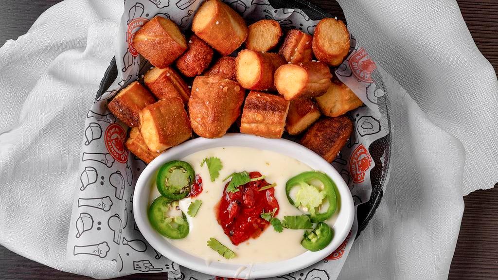 Pretzel Bites · Soft and airy deep-fried pretzel bites, served with a generous portion of queso dipping sauce topped with fresh jalapeños, salsa and cilantro.
