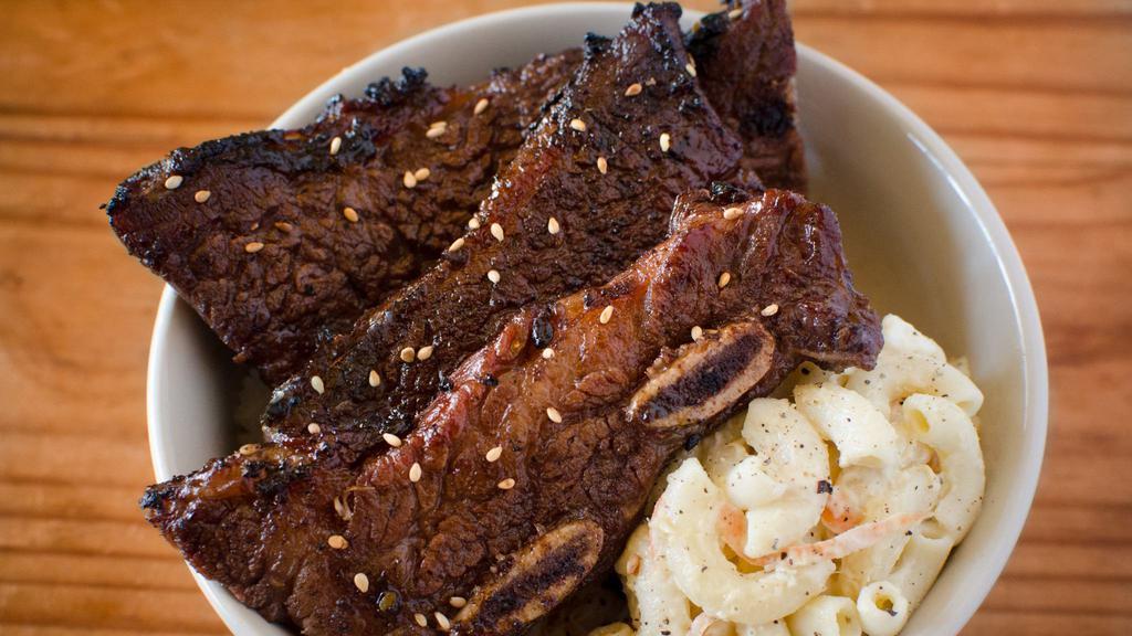 Kalbi Short Ribs · Marinated in sweet sesame soy, garlic, ginger and flamed grilled, includes rice and one choice of side.
