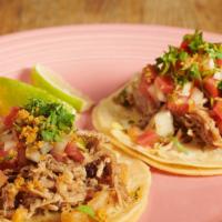 Carnitas Tacos · Two shredded pork tacos topped with cilantro and pico de gallo.