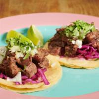 Steak Tacos · Two steak tacos topped with red cabbage, white onions, and cilantro.