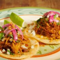 Cochinita Pibil Tacos · Two slow-roasted pork tacos topped with achiote, pickled onions, and cilantro.